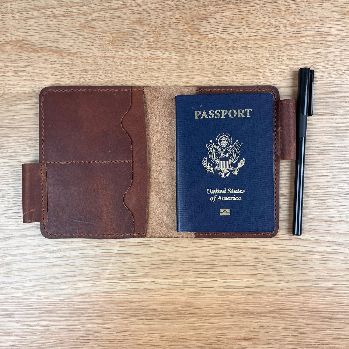 A small rectangular leather card holder with a distressed brown and white marbled finish, featuring stitched edges and two wavy card slots, photographed from above on a light wood surface.