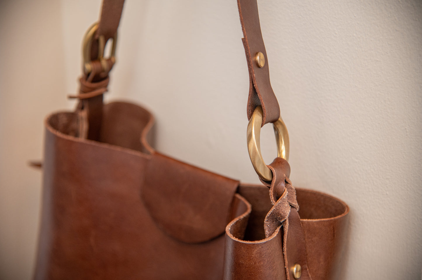 Close-up of a brown leather handbag with gold hardware on a light background